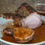 roasted rack of pork on a platter with madeira pan sauce