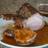 roasted rack of pork on a platter with madeira pan sauce