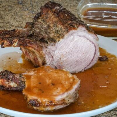 pork rack with madeira pan sauce on a serving plate.