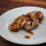 Pork tenderloin is sliced on a plate and drizzled with the reserved jalapeno glaze