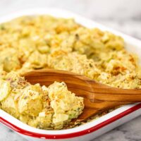 A serving dish with potato and egg salad with mayo and mustard dressing.