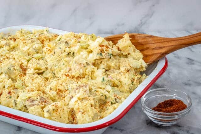 Creamy potato salad with herbs in a white dish.