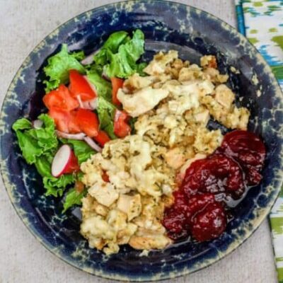 Chicken and dressing portion on a plate with cranberry sauce and a small salad.