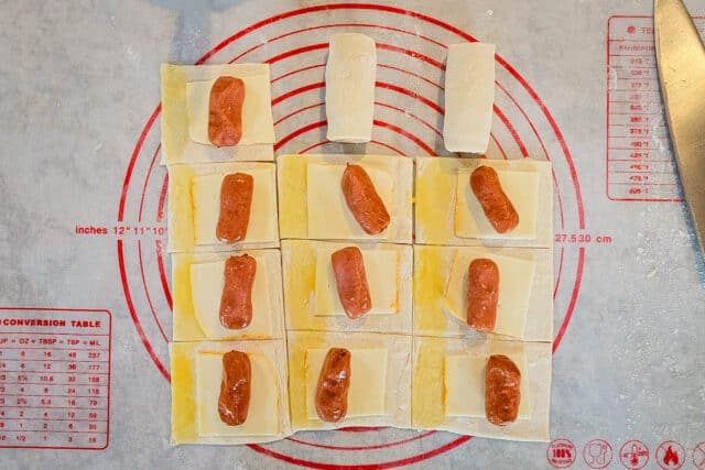 Place a little smokie on each piece of pastry and brush some of the egg wash on the edge of each square.
