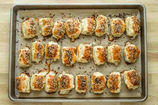 Baked puff pastry pigs in a blanket on the baking sheet.