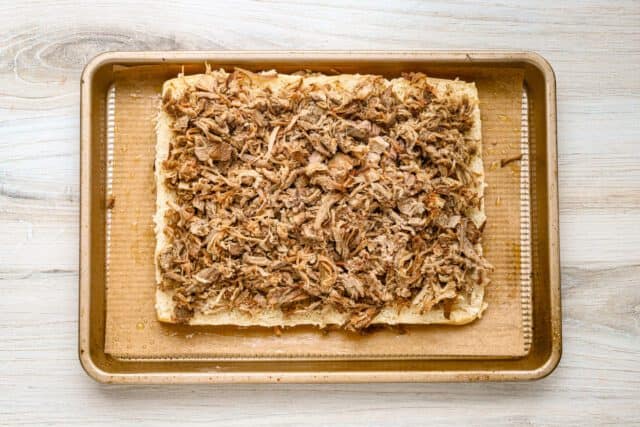Shredded cooked meat on a baking sheet.