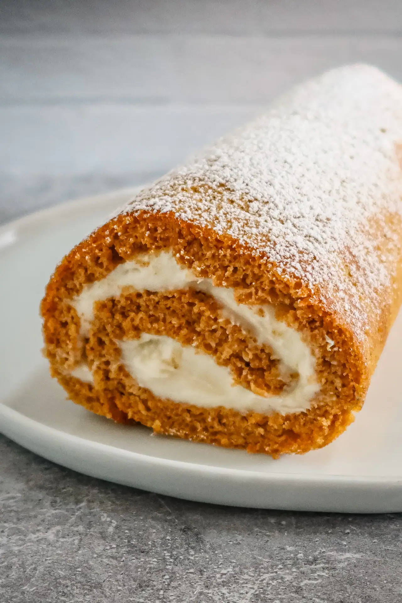 A pumpkin cake roll with cream cheese filling, dusted with powered sugar.