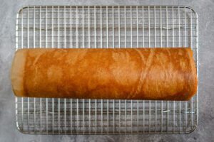 rolled pumpkin cake on a cooling rack.