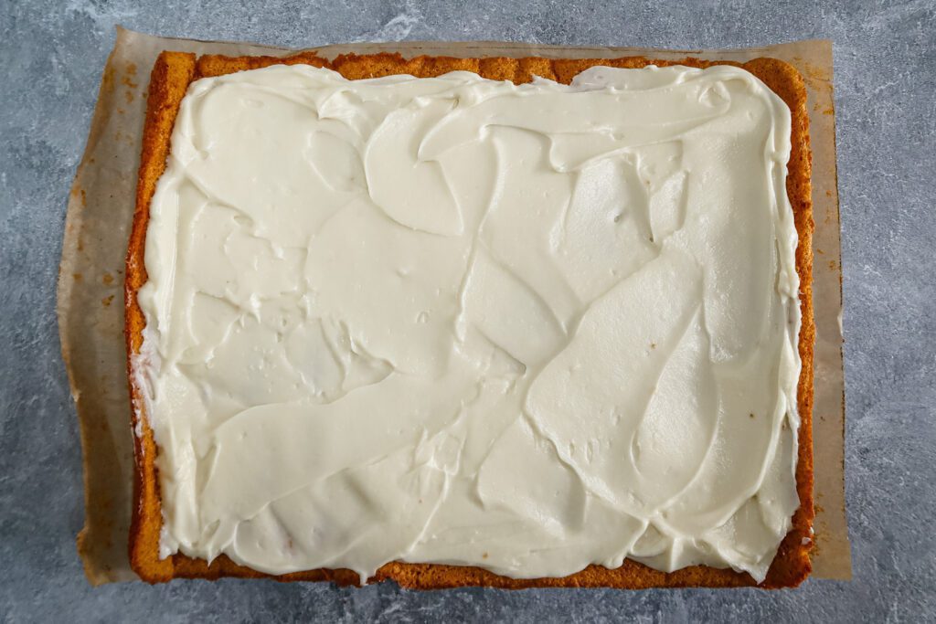 spread cream cheese over the unrolled pumpkin cake then roll it up, discarding the parchment paper.