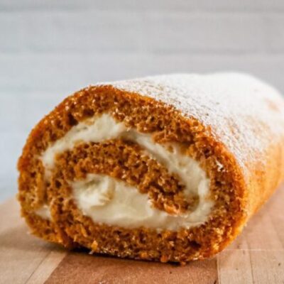 pumpkin cake roll with cream cheese filling on a cutting board