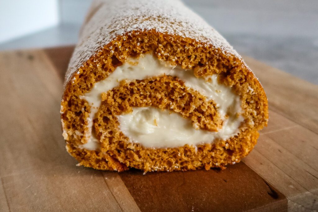 pumpkin roll with cream cheese filling on a cutting board