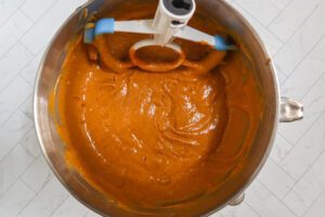 Mixing pumpkin cake batter with an electric mixer.