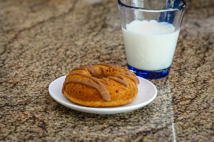 A baked pumpkin doughnut with a glass of milk.