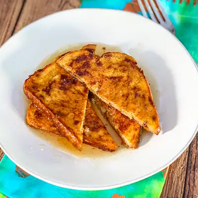 Pumpkin French toast sliced, on a plate with syrup and a fork.