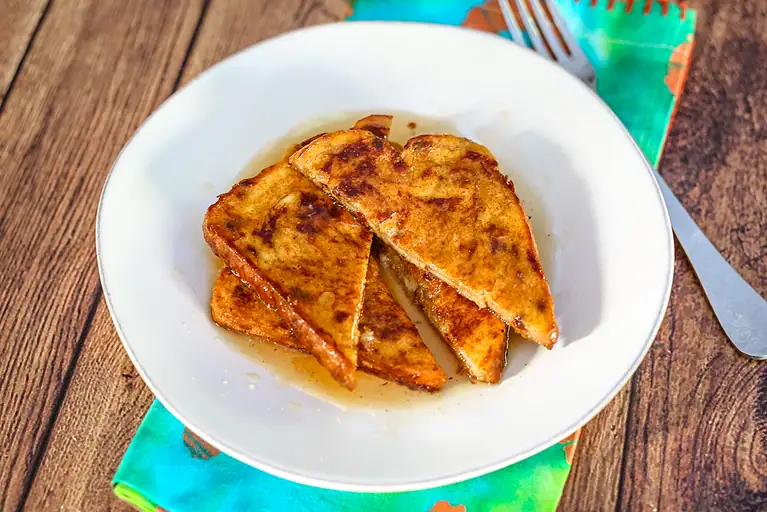 Pumpkin French toast sliced, on a plate with syrup and a fork.