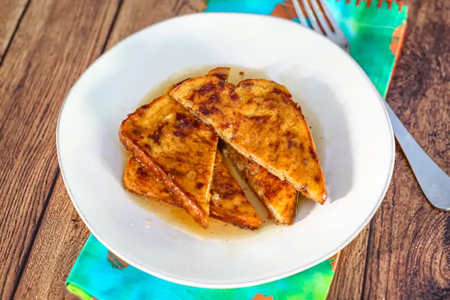 Pumpkin French toast sliced, on a plate with syrup and a fork.
