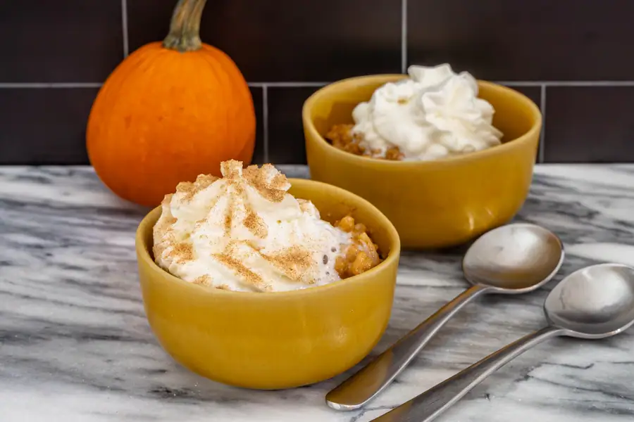 Pumpkin rice pudding in bowls with whipped cream.