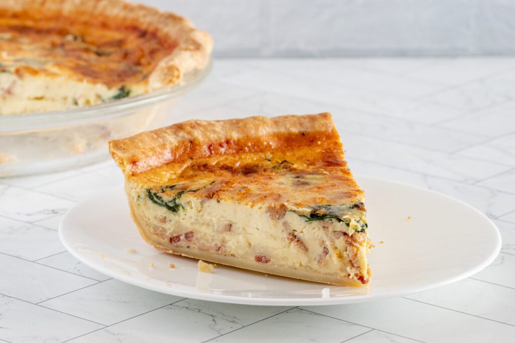 A slice of quiche lorraine with spinach and bacon