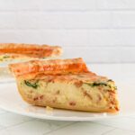 A slice of quiche lorraine with spinach