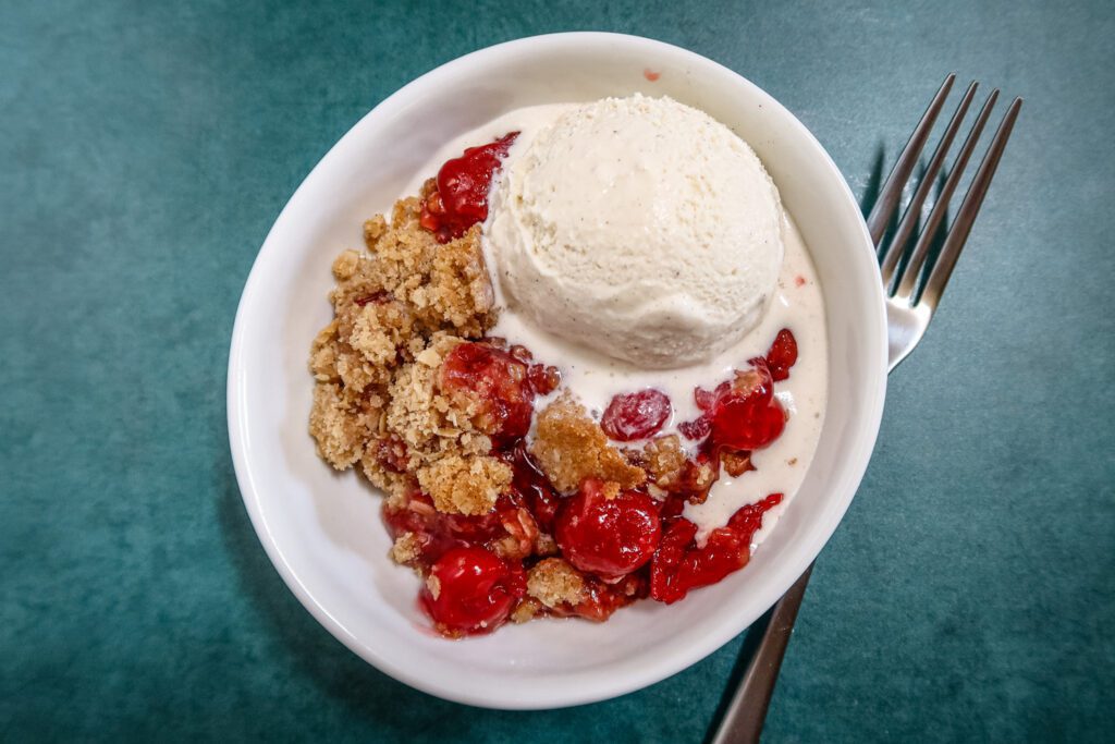 quick and easy cherry crisp in a dessert dish with ice cream