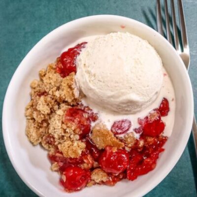 an easy cherry crisp in a dessert dish with a scoop of ice cream