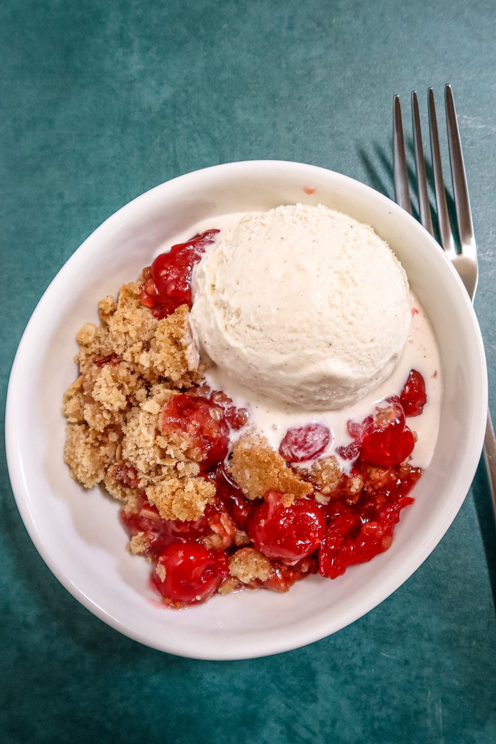 an easy cherry crisp in a dessert dish with a scoop of ice cream