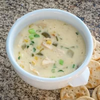 Creamy chicken and vegetable soup in a white mug.