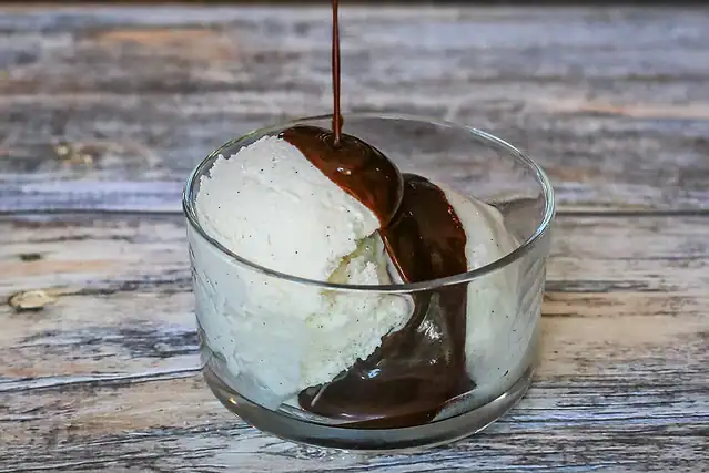 Drizzling chocolate sauce over ice cream.