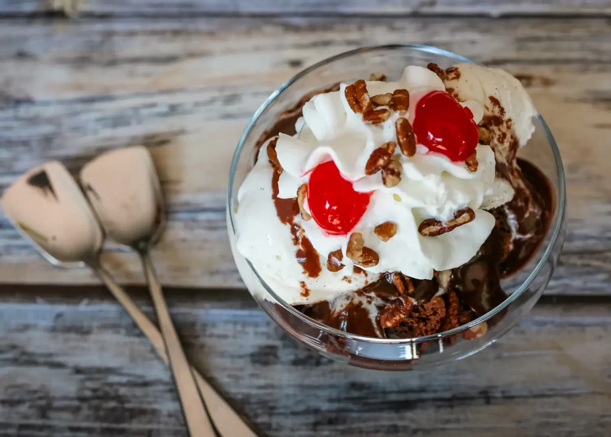 A brownie sundae with vanilla ice cream, quick chocolate sauce, whipped cream, and cherries.
