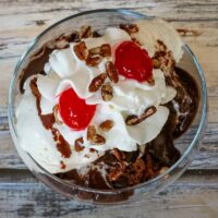 A brownie sundae with vanilla ice cream, quick chocolate sauce, whipped cream, and cherries.