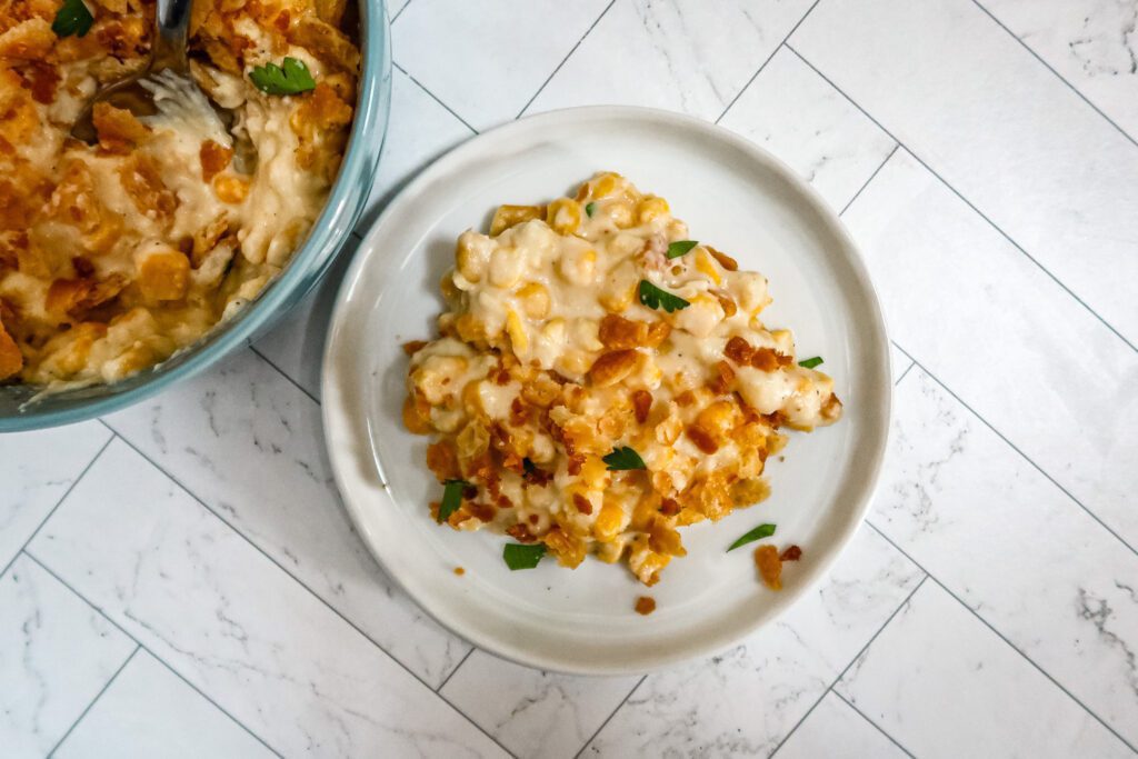 quick stovetop scalloped corn on a small plate with a serving bowl on the side