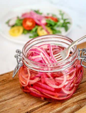 quick pickled onions in a canning jar with a salad in the background