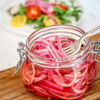 quick pickled onions in a canning jar with a salad in the background