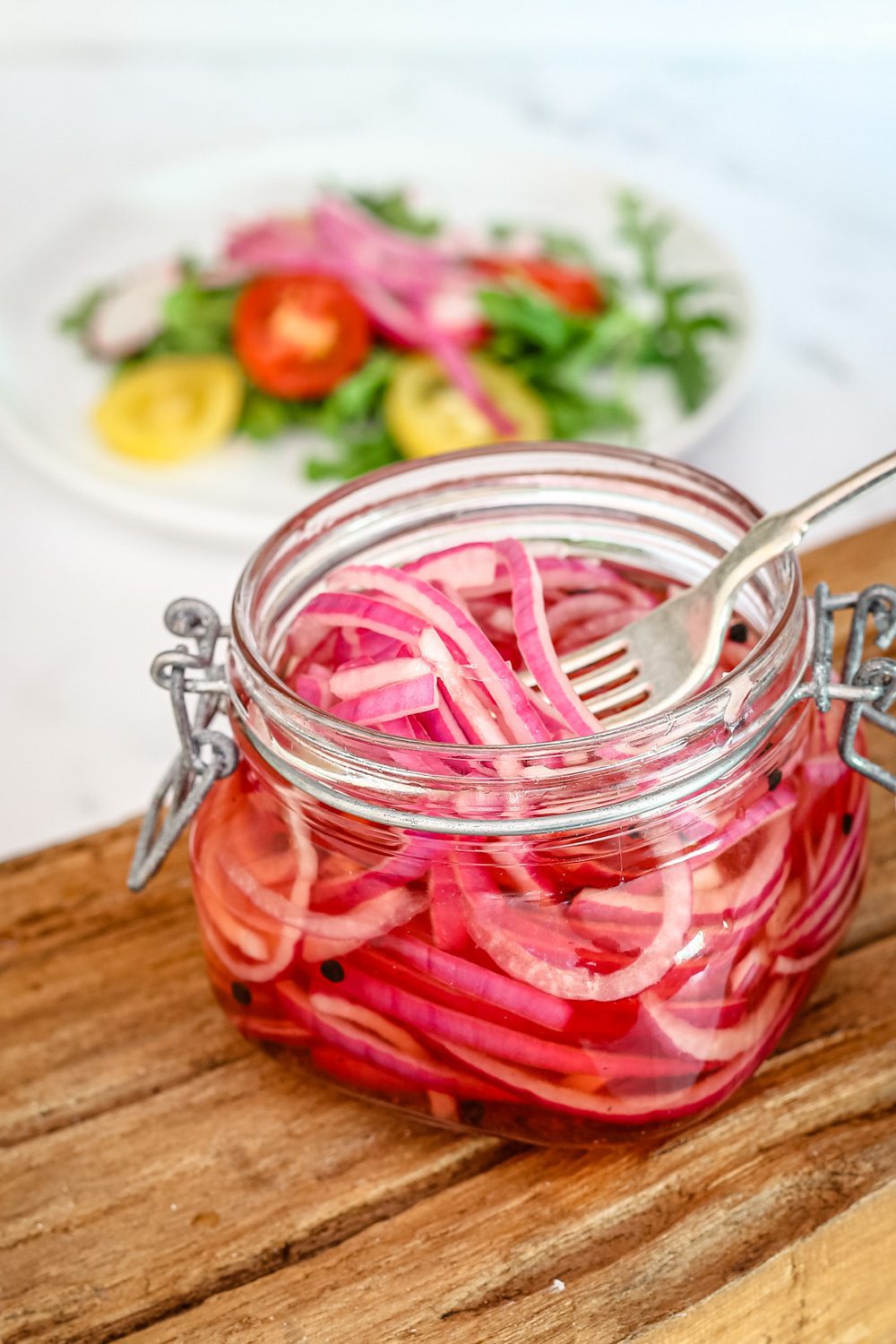quick pickled onions in a canning jar with a salad in the background