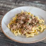 quick beef stroganoff over noodles on a plate