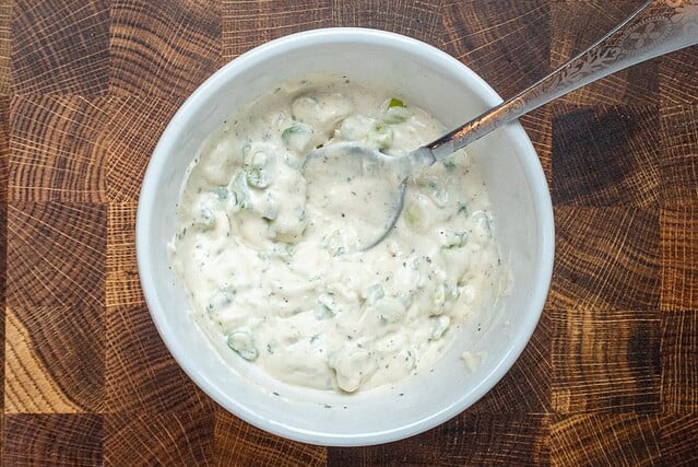 The ranch dressing mixture in a bowl with green onions, sour cream, and mayonnaise.