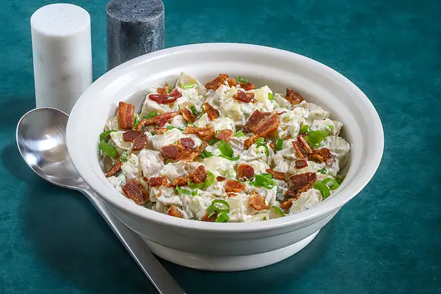 Ranch potato salad with bacon and green onion garnish.