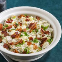 Creamy potato salad topped with crispy bacon and chopped green onions.