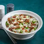 Creamy chicken salad with bacon and green onions in a white bowl.