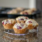 raspberry muffins on a cooling rack with the muffin tin in the background