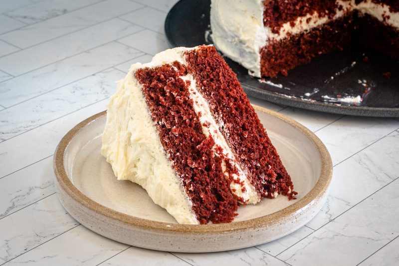 A slice of red velvet cake frosted with ermine frosting.