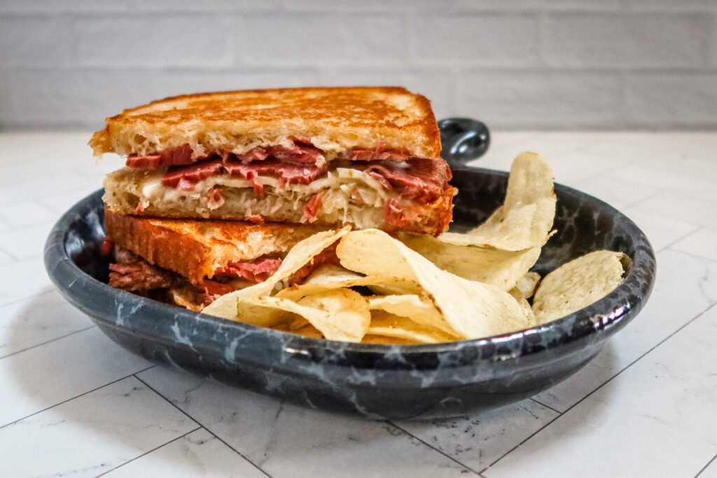 reuben sandwich on a luncheon plate with chips