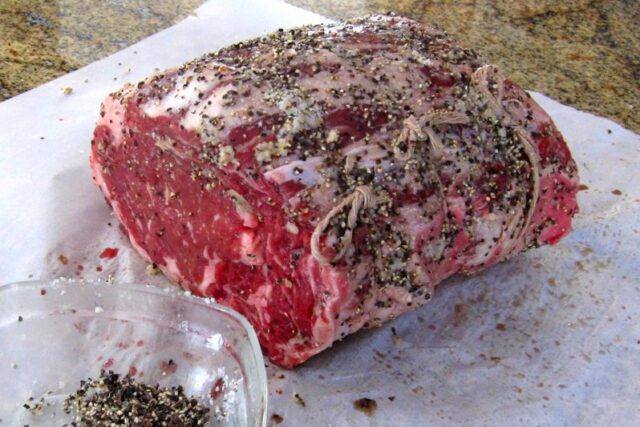 preparing the rib eye roast with herbs and garlic