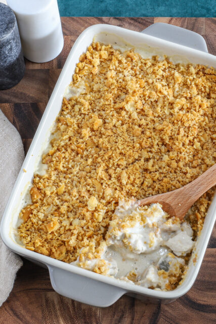 Serving the Ritz chicken casserole with a spoon and salt and pepper in the background.