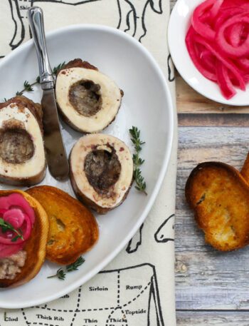 roasted bone marrow on an appetizer plate with pickled onions and crostini