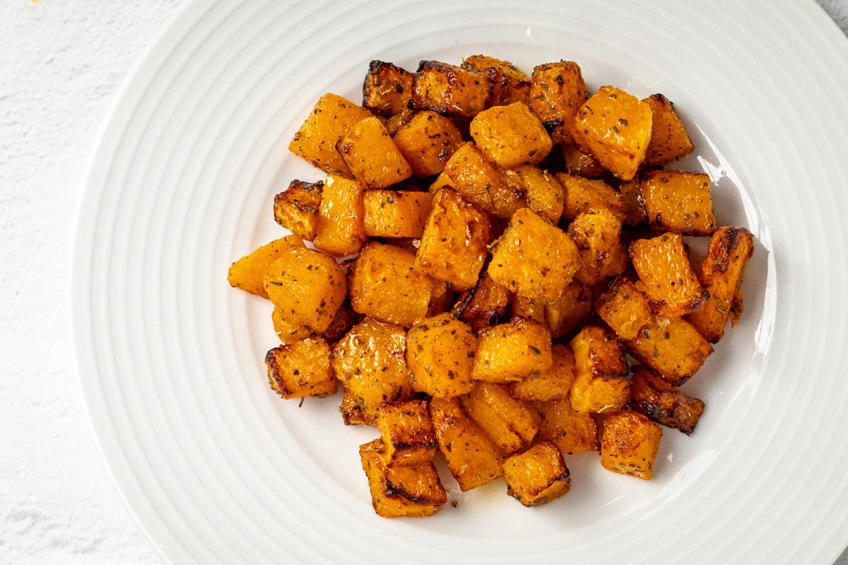 Cubed butternut squash on a plate, glazed with balsamic vinegar reduction.