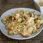roasted cauliflower with cheddar cheese sauce on a serving platter.