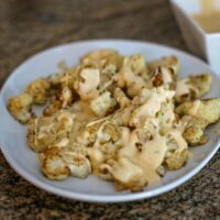 roasted cauliflower with cheddar cheese sauce on a serving platter.