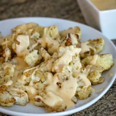 roasted cauliflower with cheddar cheese sauce on a serving platter