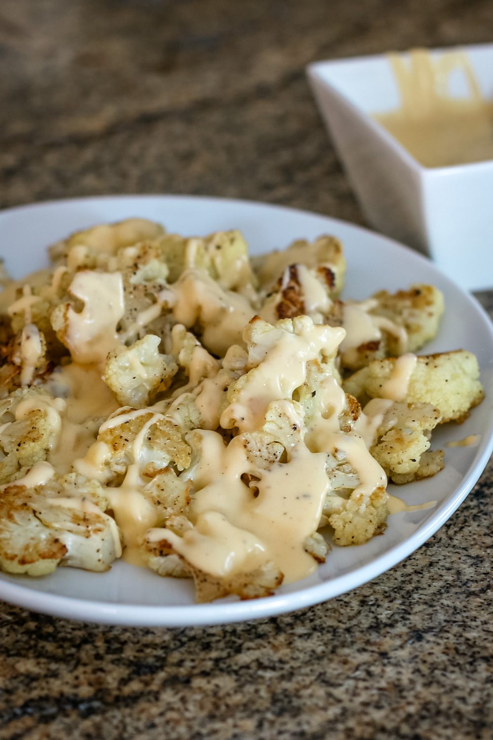 roasted cauliflower with cheddar cheese sauce on a serving platter